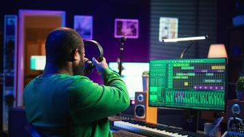 Music composer adding tracks as sound effects for a new song, recording sounds on electronic piano synthesizer. Songwriter audio technician editing and mixing tunes on software. Camera B. video