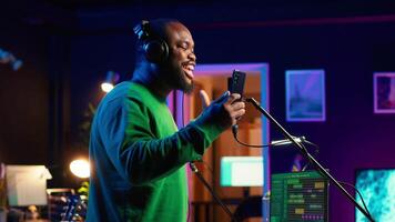 Young artist singing his new song creation on microphone gear, editing his recordings to adjust volume levels with mix and master techniques. Singer composing a melody, stereo tools. Camera A. video