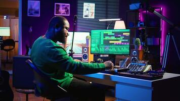 Artist playing piano electronic keyboard and recording new sounds, producing new midi controller notes in his home studio. Audio producer working with digital audio workstation software. Camera B. video
