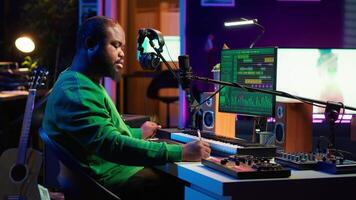 Composer writes verses and ideas to develop original song in home studio before recording new audio files. Songwriter using musical equipment and his imagination, artist composes music. Camera A. video