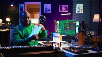 Skilled performer explaining sheet with musical notes on online tutorial, internet lessons in home studio. Producer artist teaching how to read acoustical notation, playing piano. Camera B. video