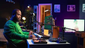 Composer writes verses and ideas to develop original song in home studio before recording new audio files. Songwriter using musical equipment and his imagination, artist composes music. Camera B. video