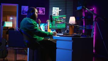 Skilled composer writing rhymes and lyrics to create new music in home studio, thinking about harmonic notes and verses to compose cool songs. Songwriter producing soundtracks with gear. Camera B. video