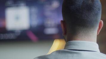 A business company's director takes a break from work in a modern office and indulges in gaming, using a joystick to play games on a TV, combining leisure and relaxation with a dash of office video