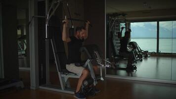A man engaged in an intense workout session at a modern gym featuring a stunning scenic view video