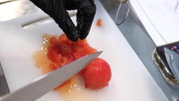cut peeled tomato into squares large knife hands in black latex gloves cook video