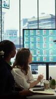 Vertical Business associates collaborating at the conference table in boardroom, utilizing smart technology and monthly statistics to present analysis of market trends and economic forecasts. Camera B. video