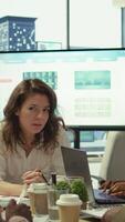 Vertical Financial expert showing statistics data on papers in a conference room, briefing meeting with staff for a presentation. Coworkers studying sales reports to adapt within market needs. Camera B. video