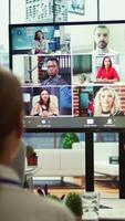 Vertical Company employees attending a meeting via videocall with investors, discussing about the future of the enterprise. Advisory board and workers examining infographics data for management. Camera B. video