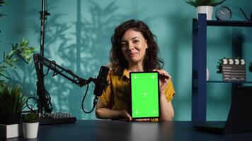 Jolly woman filming tech tutorial on how to repair damaged mockup tablet. Joyous tech professional in home studio teaching subscribers to install operating system on isolated screen device, camera B video