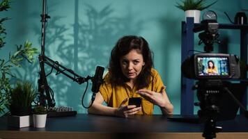 Streamer doing live broadcast, reading juicy text messages from mobile phone screen. Influencer commenting about social media posts on cellphone, talking with viewers, camera B video