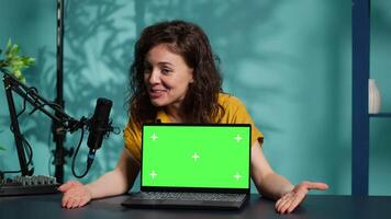 Happy content creator being sponsored by partnering brand to do green screen laptop unboxing. Upbeat technology guru does influencer marketing, doing mockup notebook product placement, camera A video