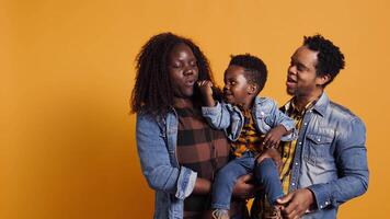 African american mom and dad teaching their son how to sing in studio, learning to perform songs on microphone from a young age. Adorable little boy singing a new melody. Camera B. video