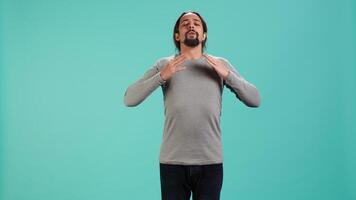 Portrait of man inhaling and exhaling to relax and gain positive energy, eliminating stress. Person doing breathing exercises for wellbeing, isolated over studio background, camera A video