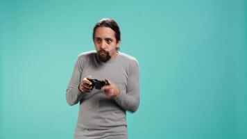 Upbeat person playing intense gaming console game, having fun, isolated over studio background. Joyous man pleased after being victorious in videogame, defeating all enemies using gamepad, camera B video
