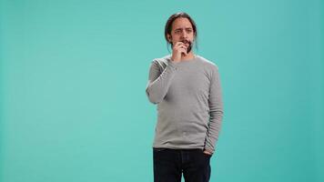 Portrait of man feeling perplexed by confusing information, isolated over studio background. Person scratching head, looking around with puzzled facial expression, camera A video