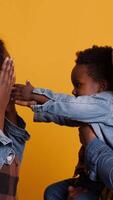 Vertical African american happy family fooling around together on camera, smiling parents embracing their small baby boy. Cheerful young mom and dad showing affection to their toddler in studio. Camera A. video