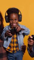 Vertical Enthusiastic father playing online games with baby boy using controller, both parents enjoying leisure time with their small kid. African american happy family play with joystick. Camera A. video