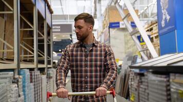 A customer with a trolley walking in a construction store in the laminate section video