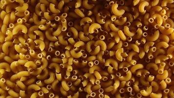 Uncooked Chifferi Rigati Pasta - Top View, Low Key. Fat and Unhealthy Food. Classic Dry Macaroni, Slowly Rotating Background. Italian Culture and Cuisine. Raw Golden Pasta Texture - Right Rotation video