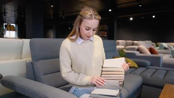 A woman choosing upholstery fabric color and texture from various colorful samples for sofa in a store video