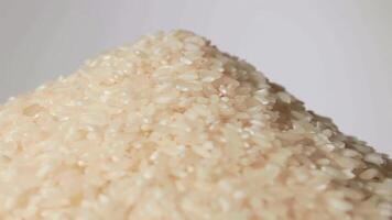 Dry Uncooked White Rice Heap on White Plate Rotating against White Background. A Pile of Raw Long Grain Rice. Asian Cuisine and Culture. Healthy Eating Ingredients. Diet Food video