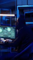 Vertical Rogue computer expert in graffiti sprayed hideaway targeting vulnerable unpatched connections, focused on getting past digital devices security and stealing valuable sensitive data, dolly in shot video