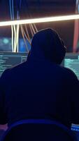 Vertical Rogue hacker using computer in abandoned basement with graffiti drawings on walls. Malicious criminal doing illegal activities in underground hideout painted in grungy style, dolly out shot video
