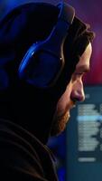 vertical hacker se escondendo dentro bunker removendo fones de ouvido para ouvir suspeito sons, sentindo-me ansioso depois de roubando dados a partir de vítimas. homem parando música, assustado sobre ser apanhado de polícia, Câmera uma fechar acima video