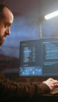 Vertical Hacker in foggy neon illuminated basement with graffiti drawings on walls using advanced technology computer, running code. Cybercriminal using dark underground warehouse as crime haven, camera A video