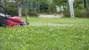 Boy running with a lawn mower in the garden. Close-up video