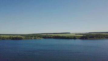 river with waves on the background of the shore with trees and a field on a summer day video