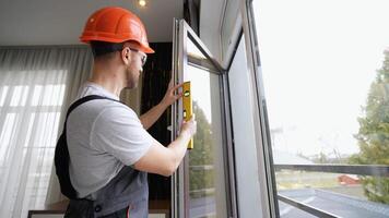 Window installer adjusting plastic windows with level tool in room at home video
