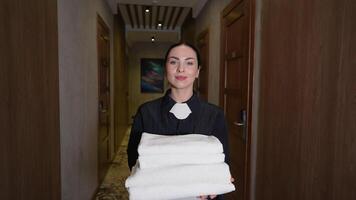 Hotel maid with white linen and towels in her hands walking in hallway video