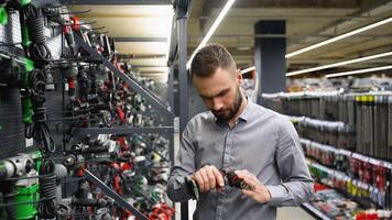 A man in a hardware store chooses a new screwdriver or drill video