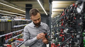 A man in a hardware store chooses a new screwdriver or drill video