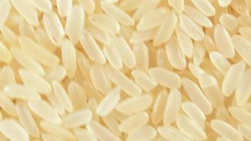 Dry Uncooked Parboiled Rice Background Rotating Counter-Clockwise - Top View. Scattered Raw Long Grain Rice. Asian Cuisine and Culture. Healthy Eating Ingredients. Diet Food. Angular Rotation Left video