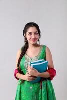 Sharp Woman in Indian Suit Holding Books in Hand While Posing in Front of Camera photo