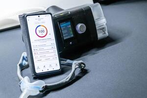 CPAP machine with nose CPAP mask and stats on smartphone display with digital app for treatment stats and medical reports or health reports and digital assistant for therapy analysis therapy reports photo