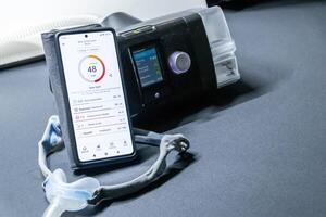 CPAP machine with nose CPAP mask and smartphone with digital app for treatment stats and medical reports or health reports and digital assistant for therapy analysis and therapy reports stats photo