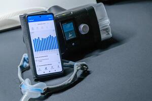 CPAP machine with nose CPAP mask and smartphone with digital app for treatment stats and medical reports or health reports and digital assistant for therapy analysis and therapy reports patient files photo