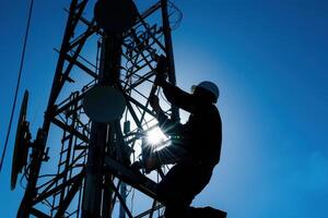 Silhouette of a telecommunication engineer working on a cell tower photo