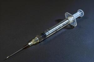 Syringe with a needle is lying on a dark background photo