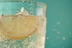 Refreshing lemon slice submerging in sparkling water with bubbles photo
