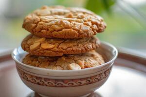 Stack of freshly baked white chocolate macadamia nut cookies overflowing a bowl photo