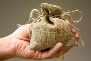 Man holding small burlap sack with string photo