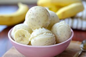 Scoops of banana ice cream topped with vanilla seeds in pink bowl photo