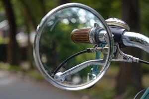 Round chrome bicycle mirror reflecting handlebars and green background photo