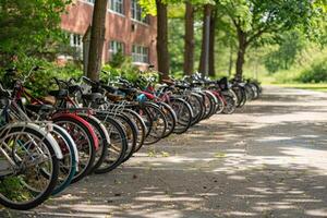 Many bicycles parked in a row in front of a school during a sunny summer day photo