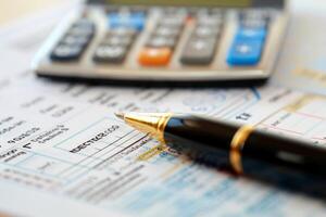 Elegant pen is lying on invoice with calculator in the background photo